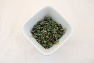 a white bowl filled with green tea on top of a white table