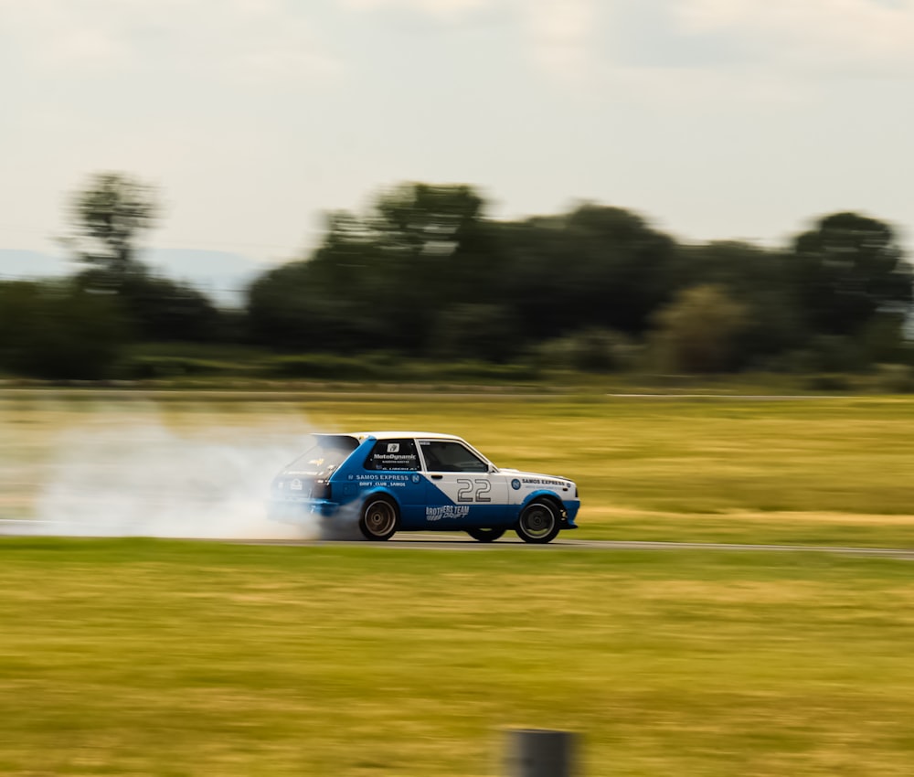 a blue and white car driving down a road