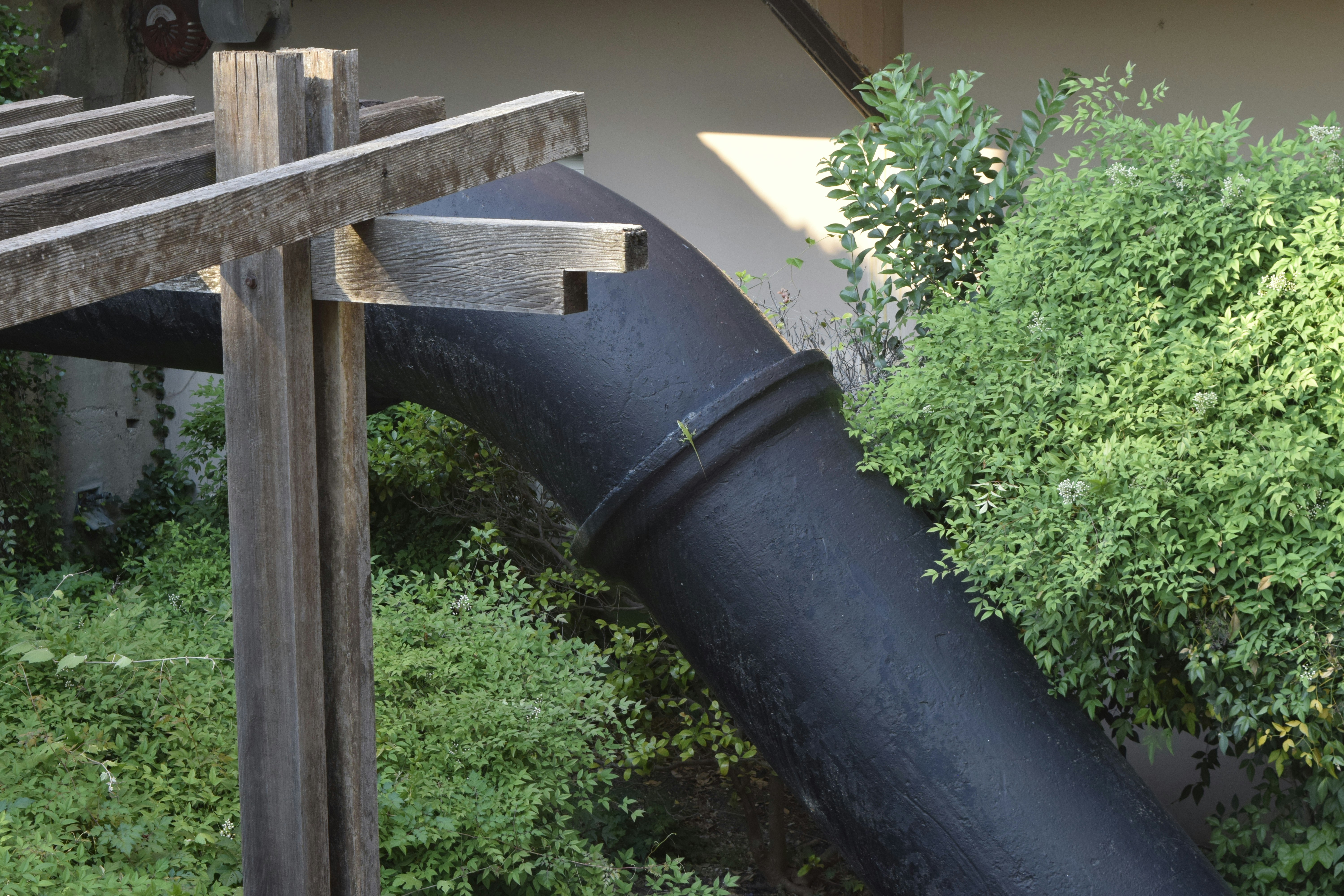 Newly painted black cast iron downpipe on a brick wall