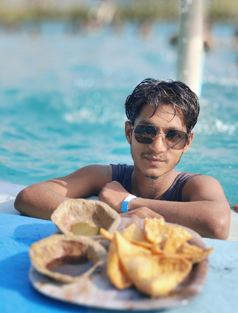 a man sitting in a pool with a plate of chips