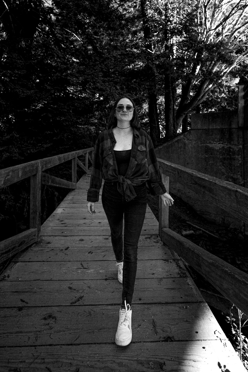 a woman walking across a wooden bridge