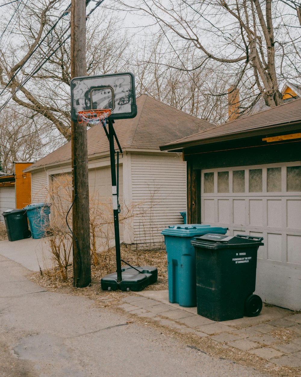 a basketball hoop and trash cans in front of a house