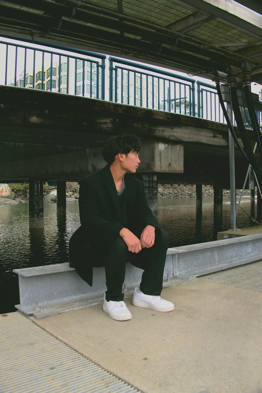 a man sitting on a ledge next to a body of water