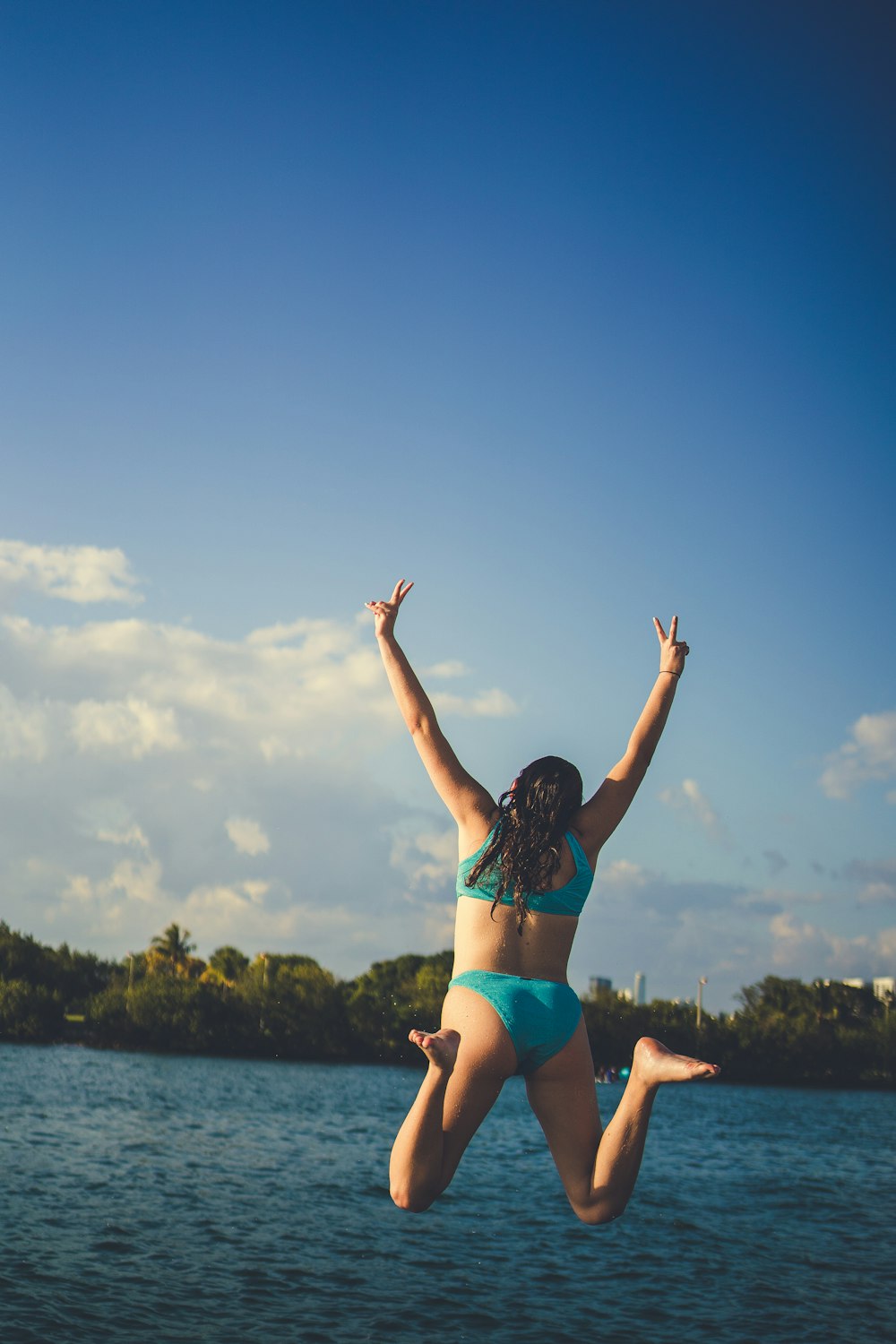 a woman in a bikini jumping into the air