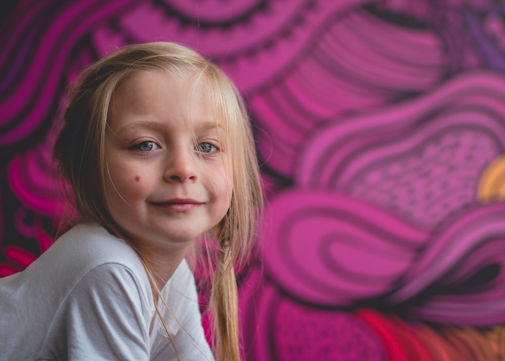 a little girl that is sitting in front of a wall