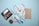 A flat lay of makeup products including a beige wallet, an eyeshadow palette, various makeup brushes with light blue handles, a compact, and a red lipstick all arranged on a light blue background.