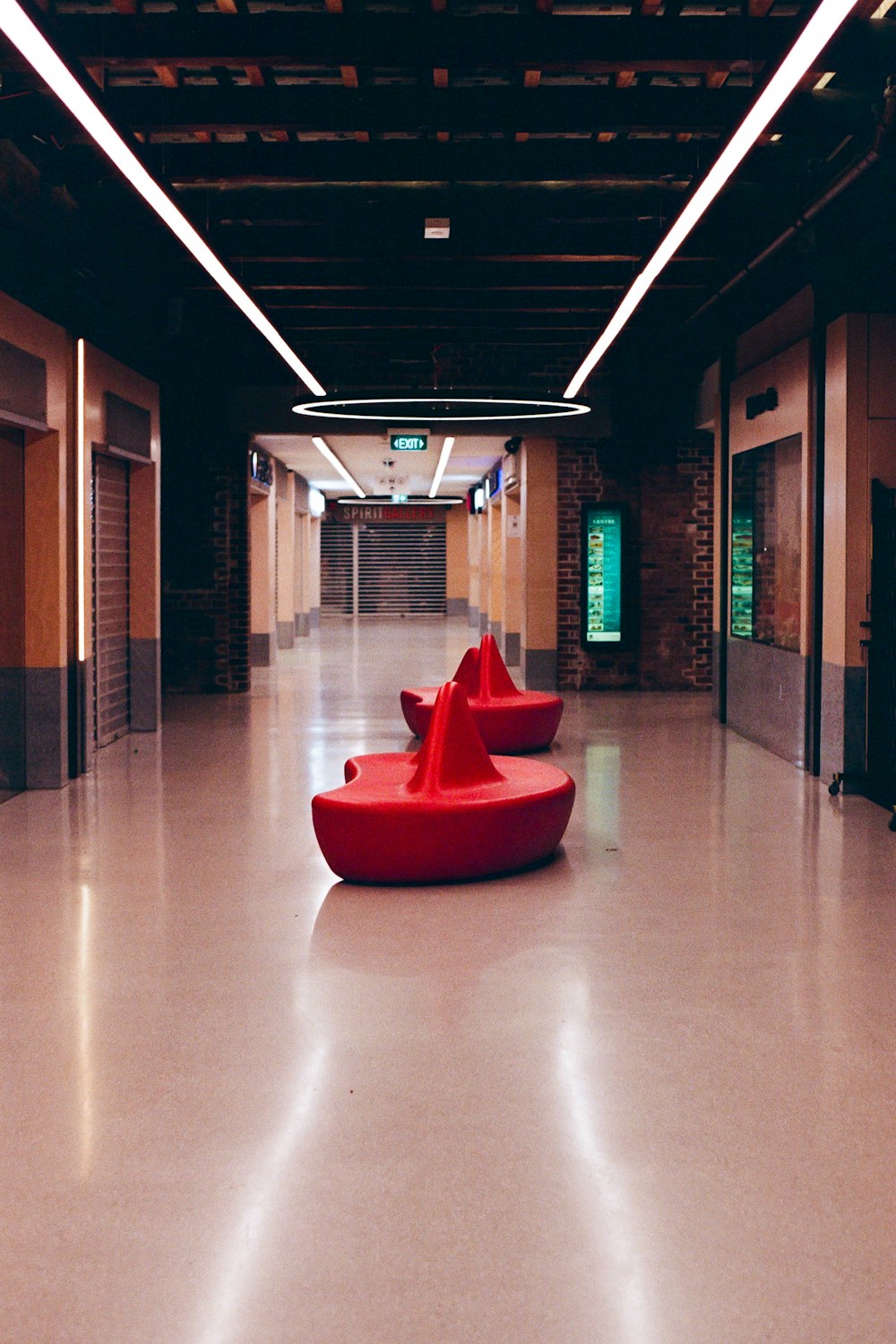 a red couch sitting in a large room next to a fire hydrant