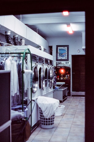 Stacked laundry baskets filled with colorful clothes ready for wash and fold service under soft lighting.