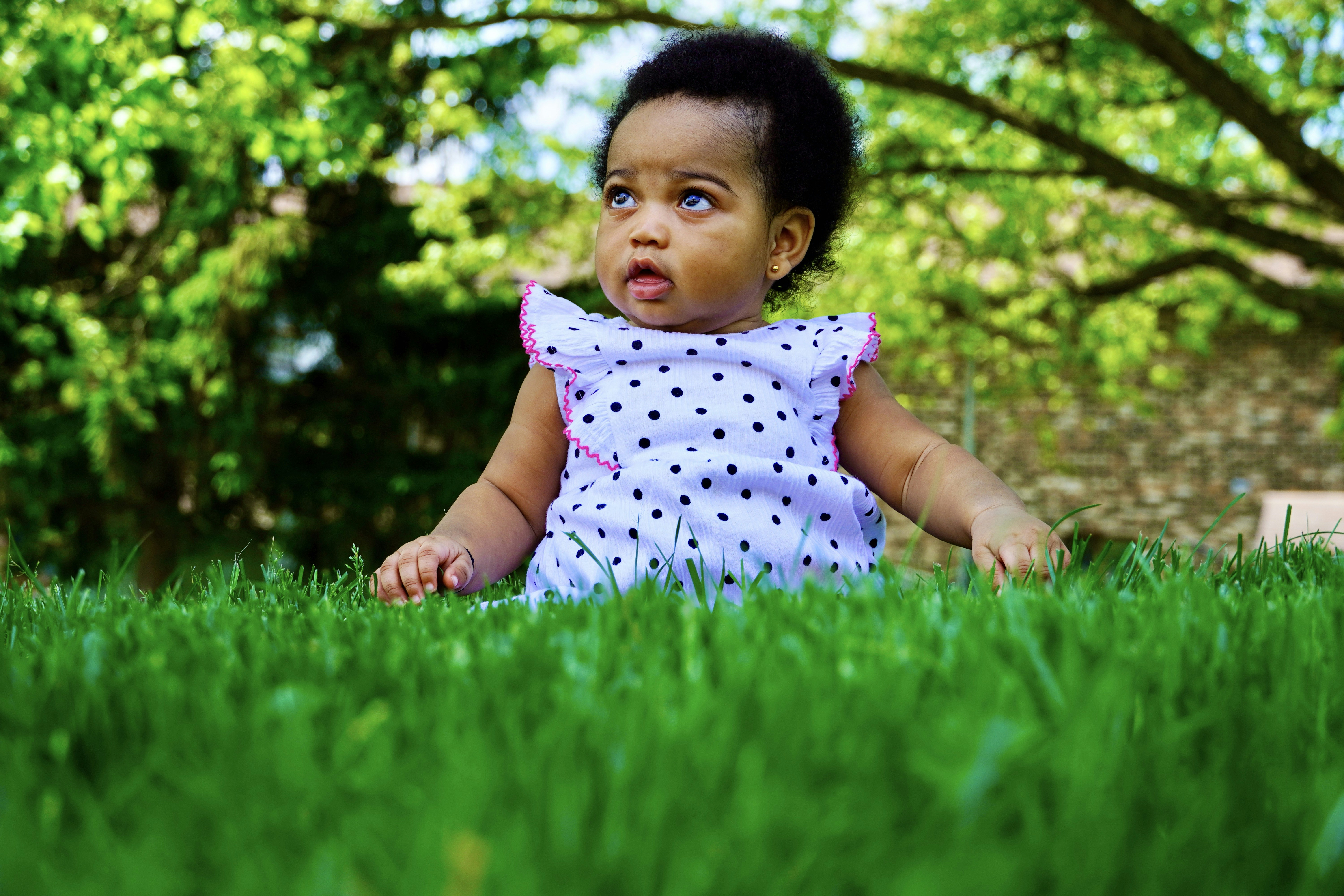 a little girl sitting in the grass with a surprised look on her face