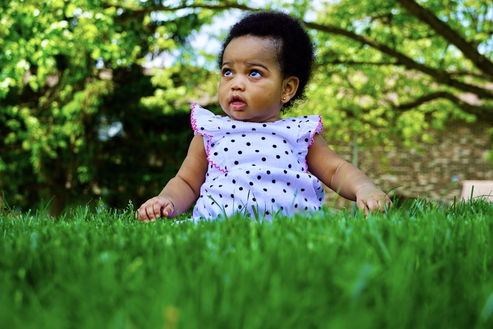 Una bambina seduta nell'erba con uno sguardo sorpreso sul suo viso