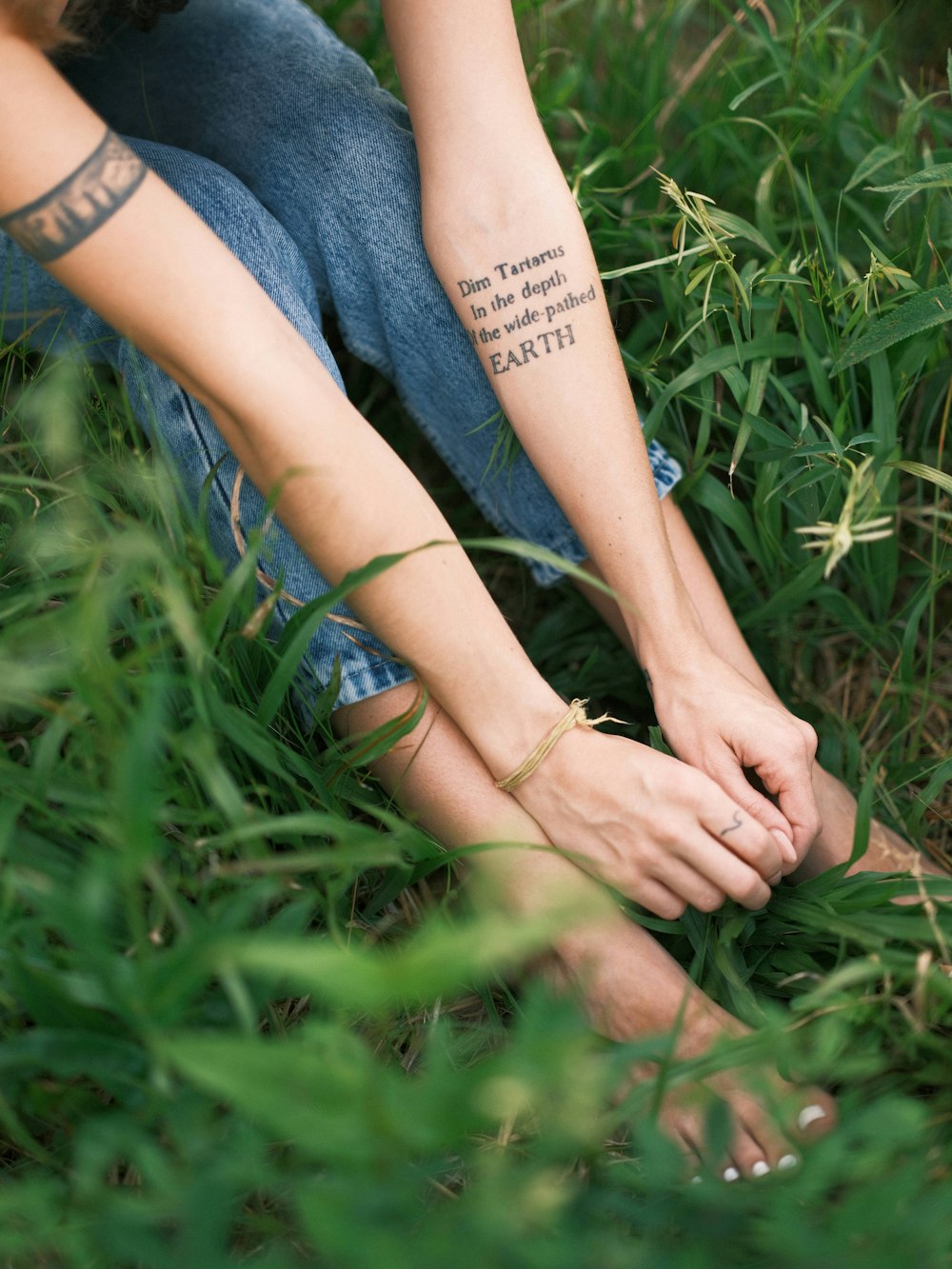 a woman with a tattoo on her arm sitting in the grass