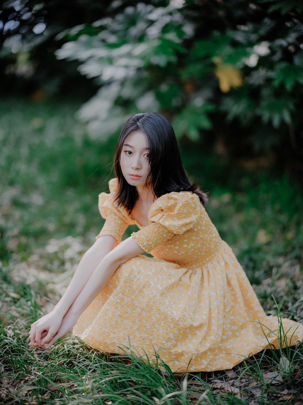 a woman in a yellow dress sitting in the grass