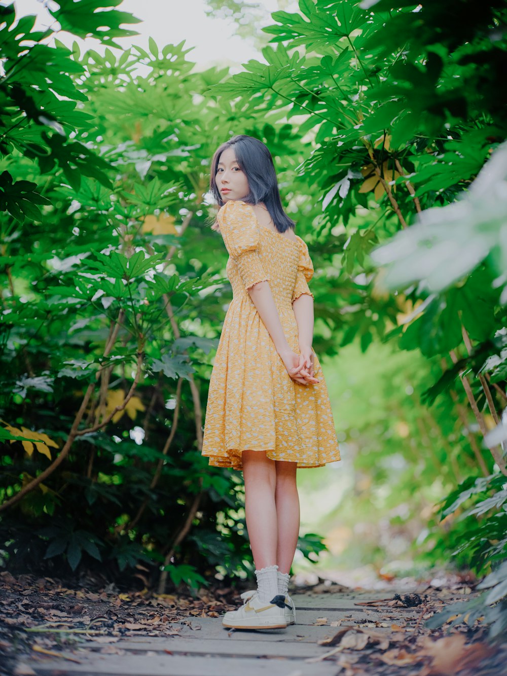 a woman in a yellow dress standing on a path