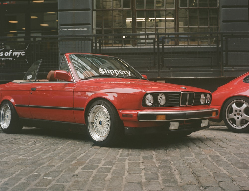 a red convertible car parked next to a red convertible car