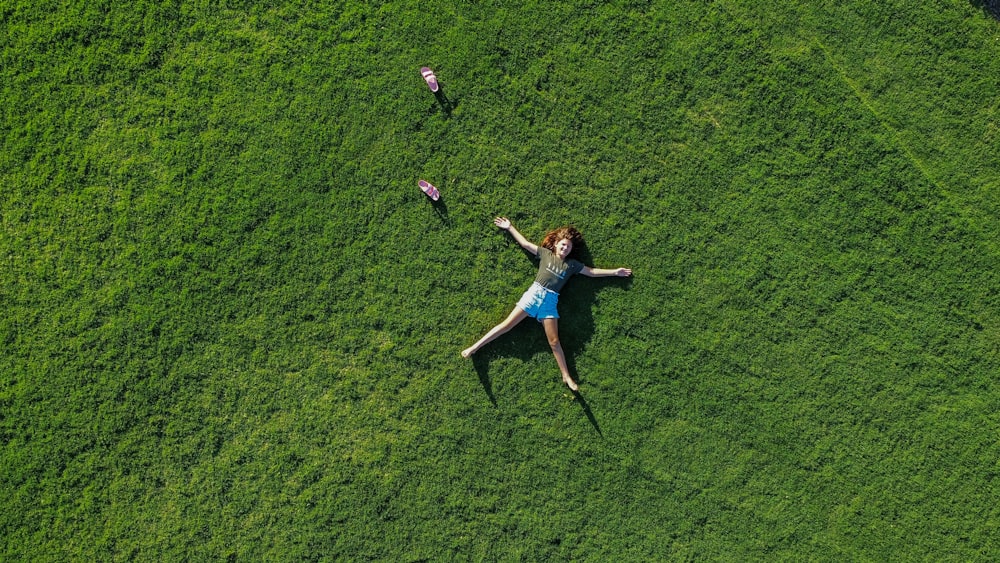 a woman laying in the grass with her arms outstretched
