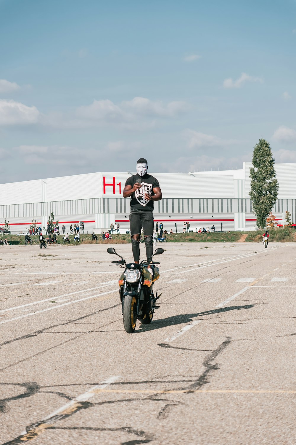 a man standing on a motorcycle in a parking lot