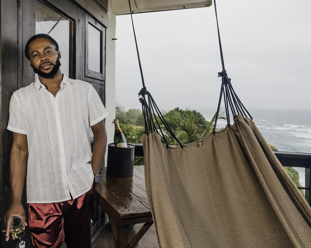 a man standing next to a hammock on a porch