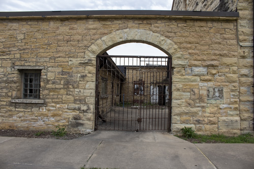 a gated entrance to a building with a brick wall