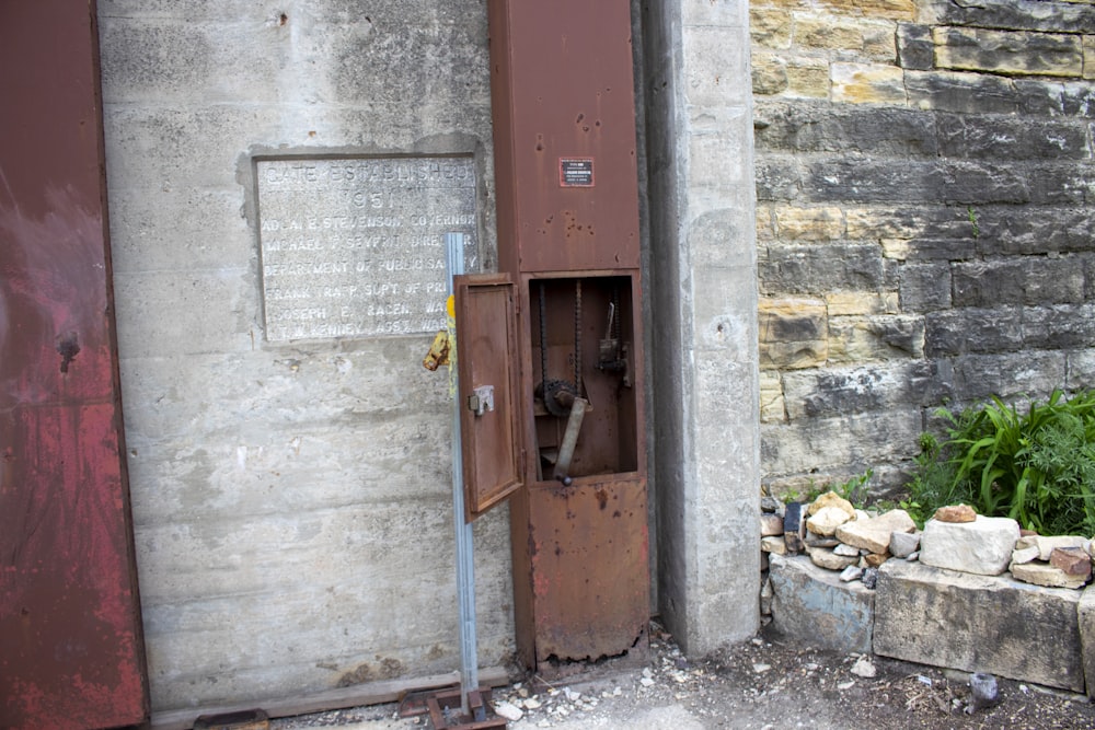 Una cabina telefónica oxidada junto a una pared de ladrillos