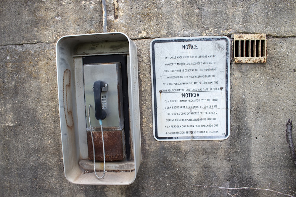 an old phone is attached to a concrete wall