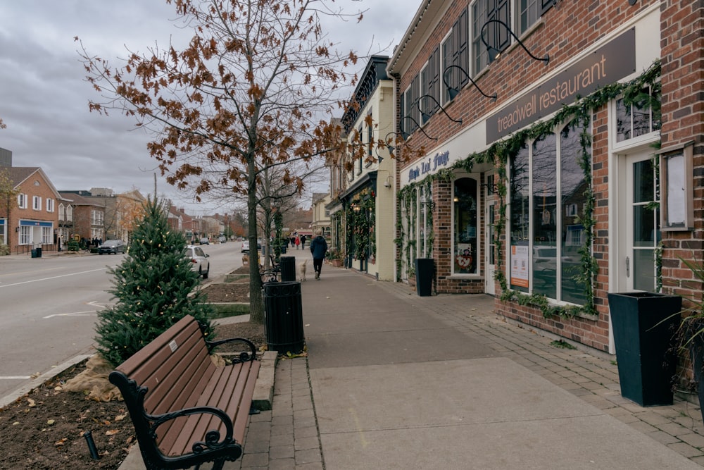 a wooden bench sitting on the side of a sidewalk