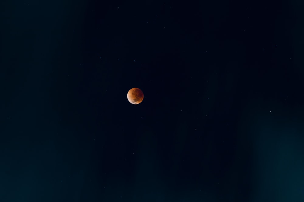 a red moon is seen in the dark sky