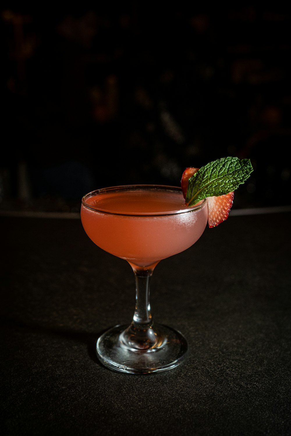 a drink in a glass with a green garnish on the rim