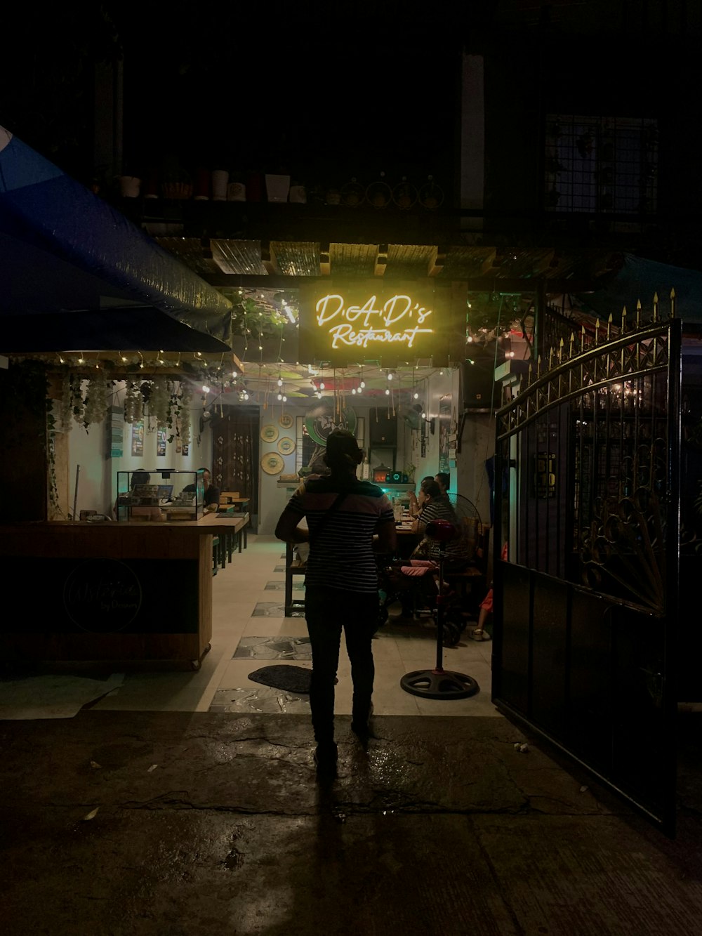 a woman standing outside of a restaurant at night