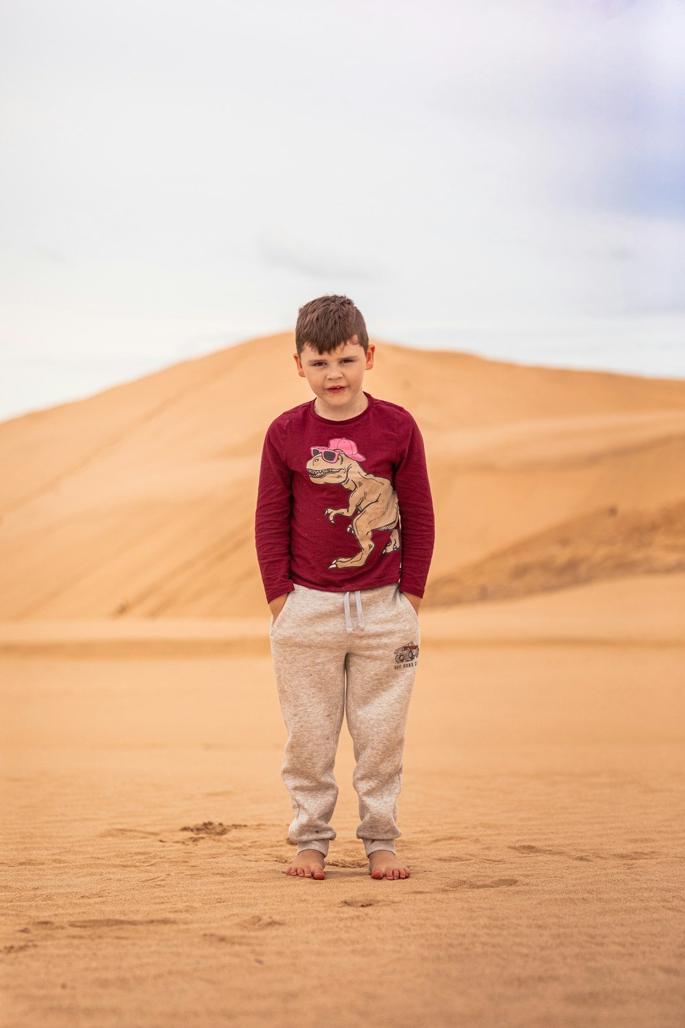 a young boy standing in the middle of a desert