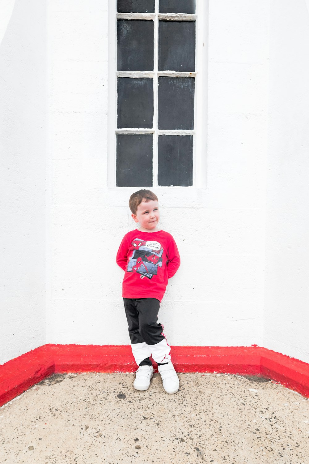 a little boy standing in front of a window