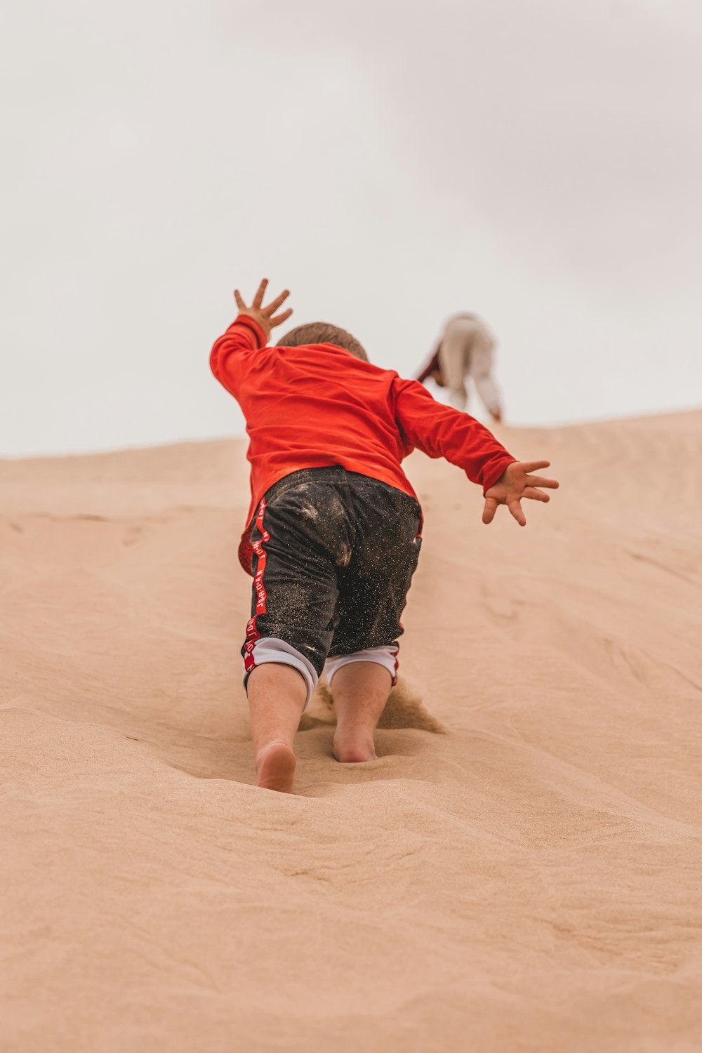 a small child in a red shirt is playing in the sand