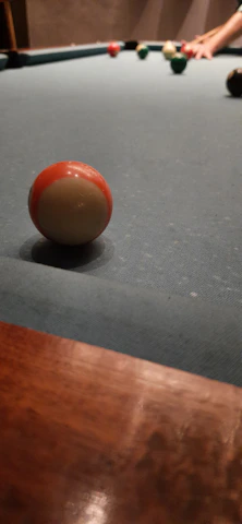 Close-up of a hand lining up a billiard shot on a green felt table under warm lighting.