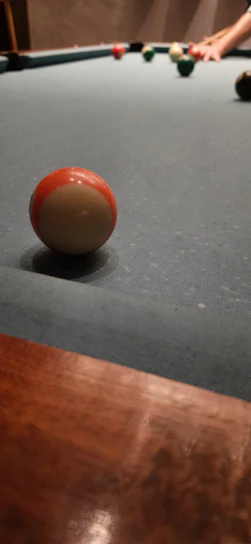 A close-up shot of a golden billiard cue resting on a green felt pool table under warm lighting.