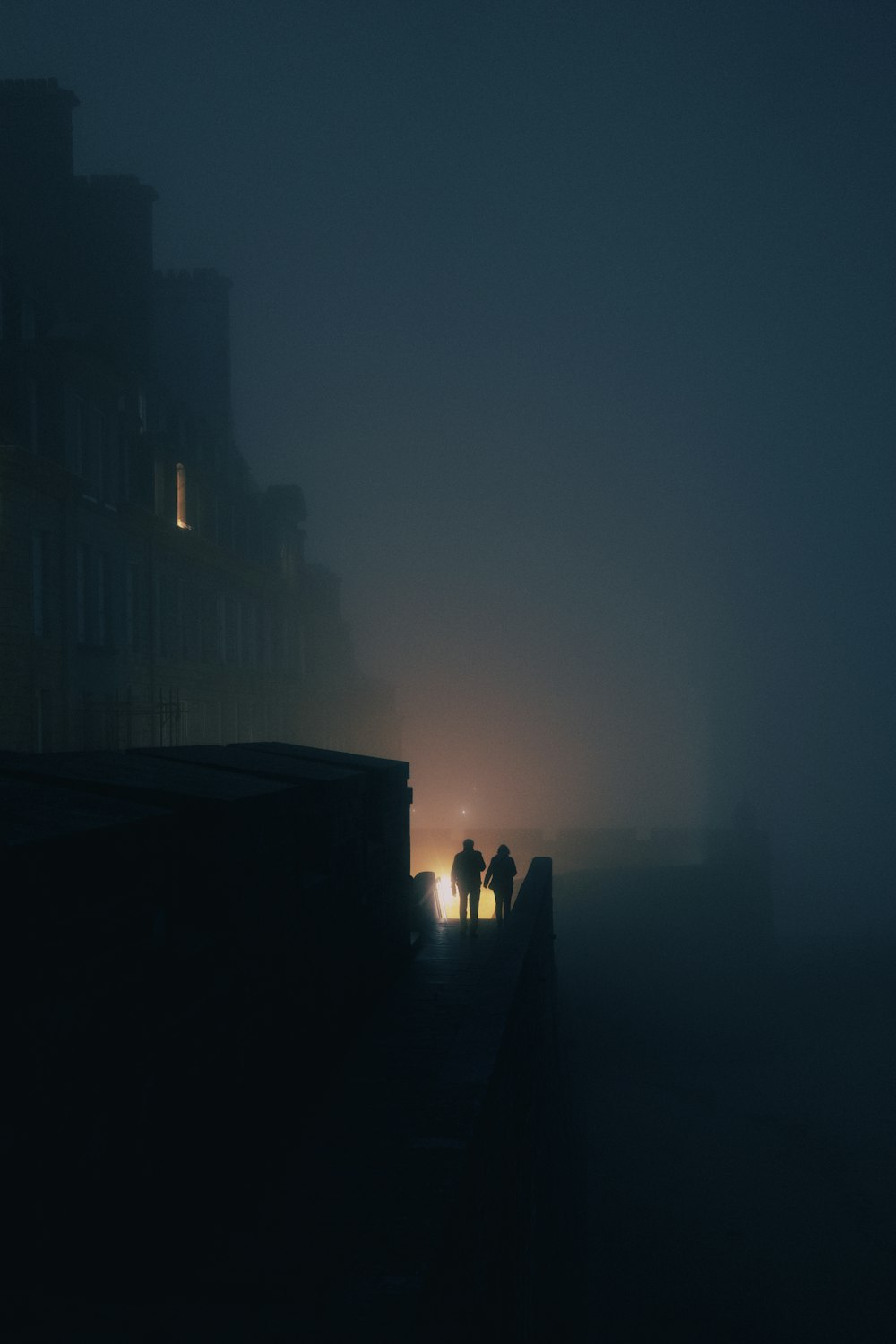 a couple of people walking down a foggy street