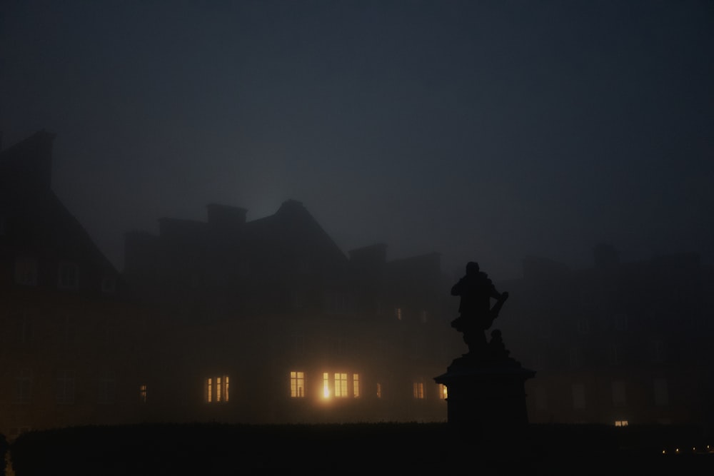 a foggy night with a statue in the foreground