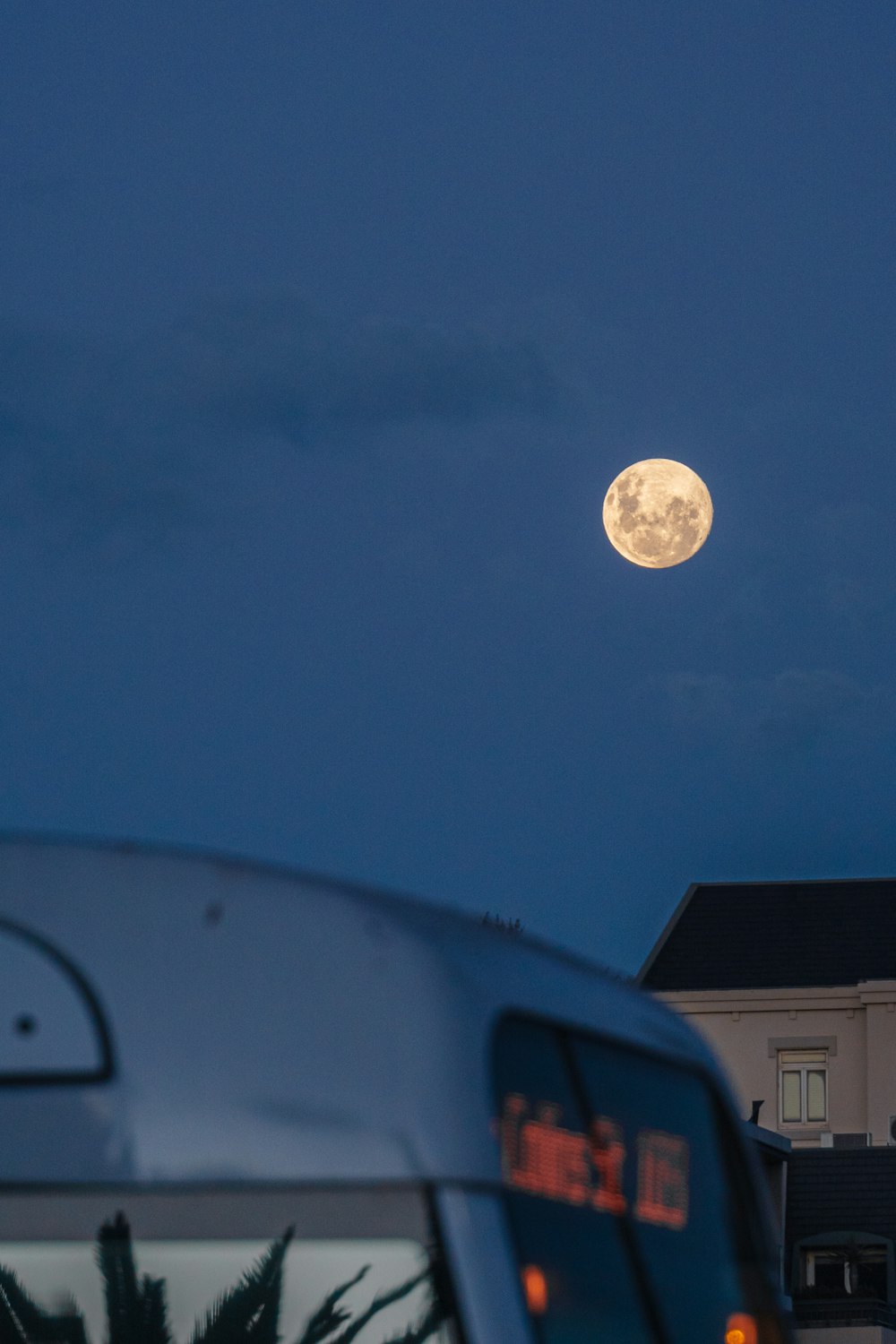 a bus is parked in front of a building with a full moon in the sky