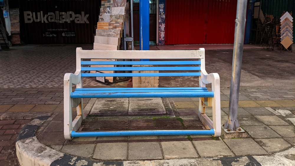 a blue and white bench sitting on the side of a road