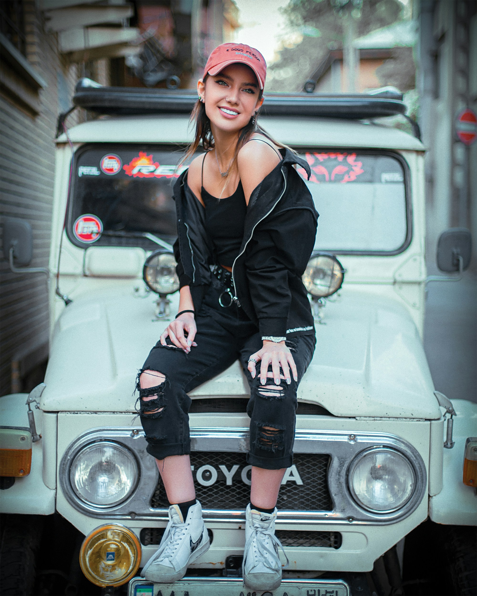 uma mulher sentada no capô de um carro