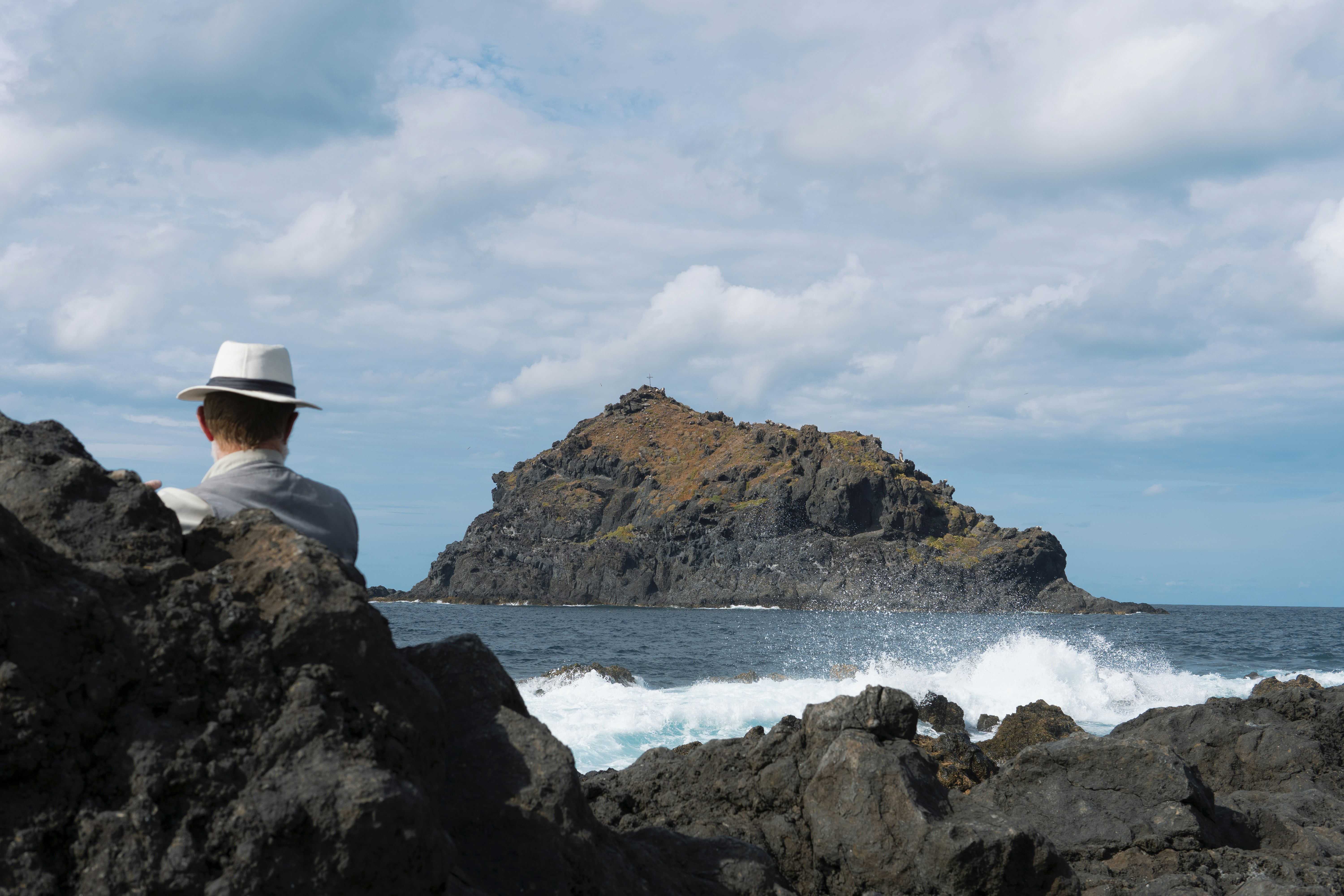 A man sitting on a rock looking out at the ocean photo – Free Garachico ...