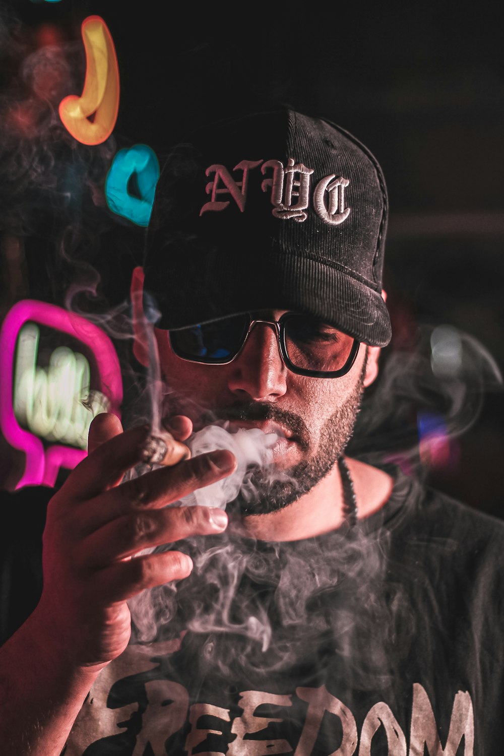 a man smoking a cigarette in front of a neon sign