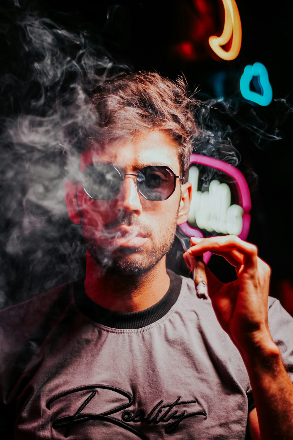 a man smoking a cigarette in front of a neon sign