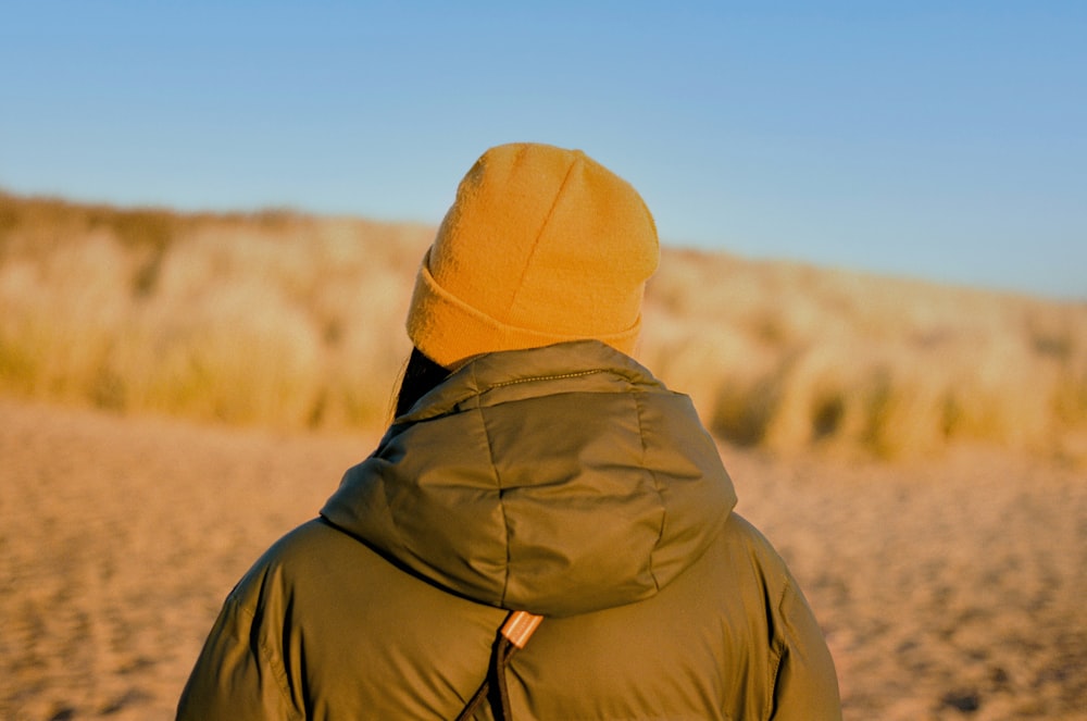 a person in a brown jacket is standing on a beach