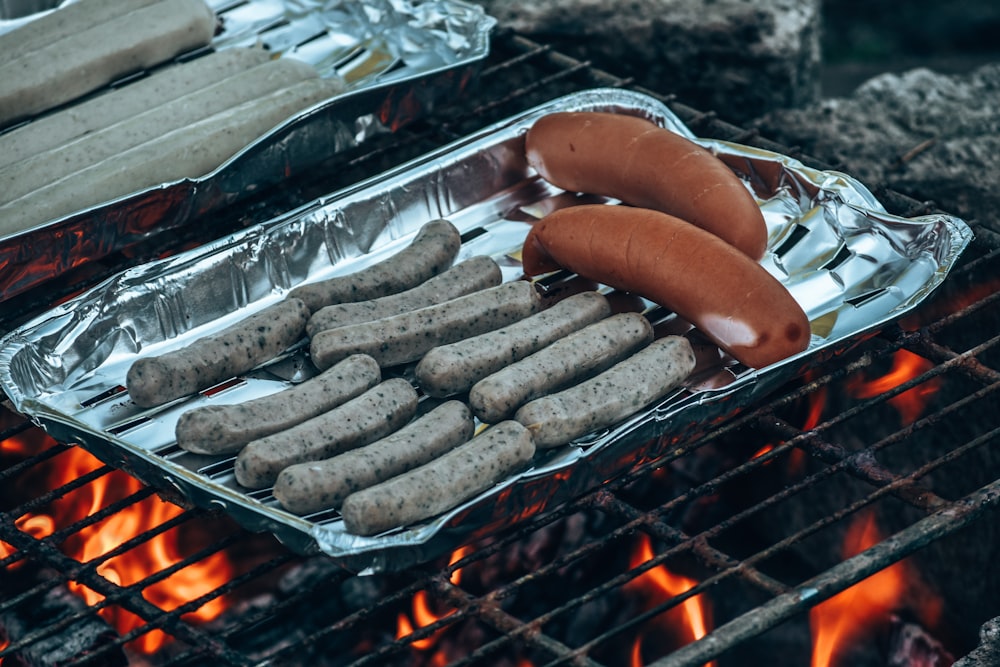hot dogs and sausages cooking on a grill