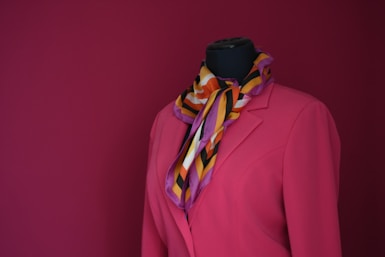 a mannequin wearing a pink coat and a multicolored scarf