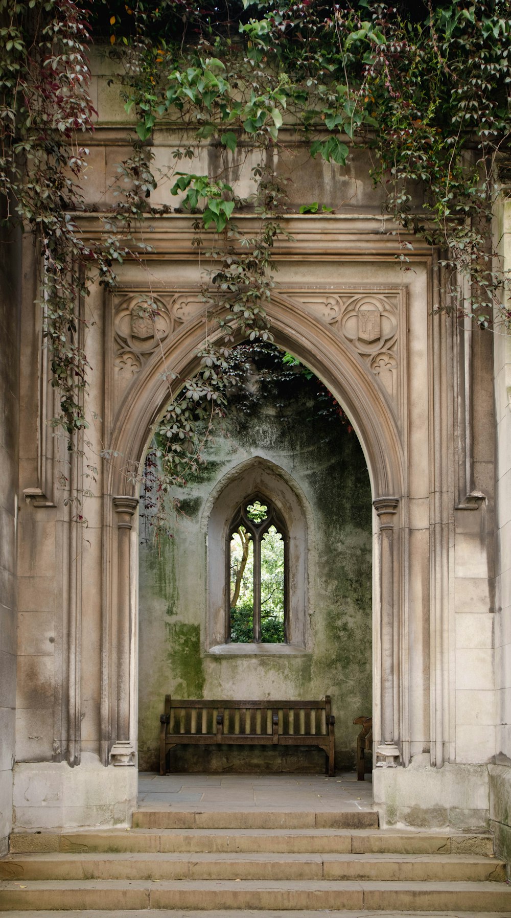 a stone archway with a bench in front of it