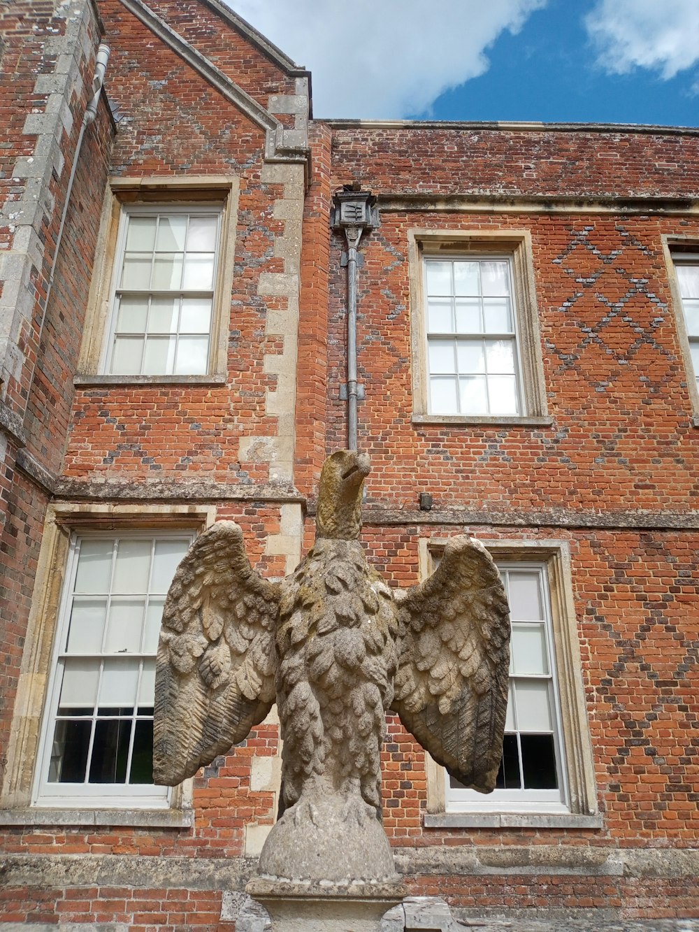 a statue of an eagle on a pedestal in front of a brick building