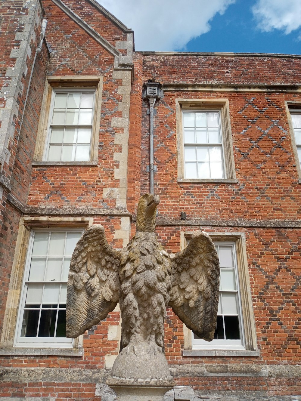 Una statua di un'aquila su un piedistallo di fronte a un edificio di mattoni