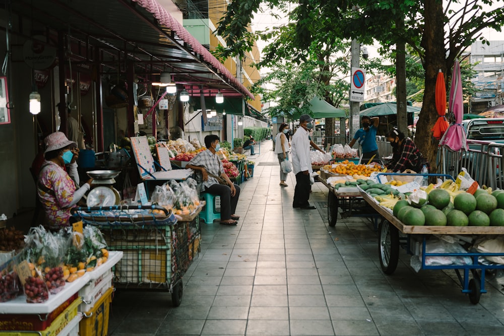 um mercado com pessoas comprando e vendendo frutas e legumes