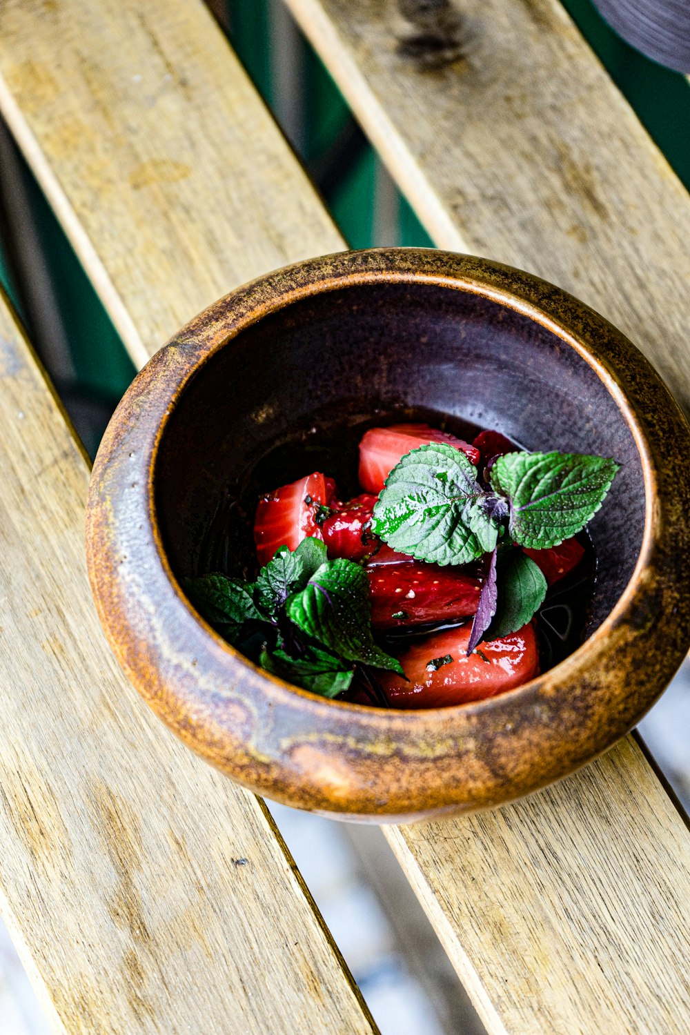 a bowl of strawberries on a wooden table