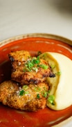 a red plate topped with meat patties and mashed potatoes
